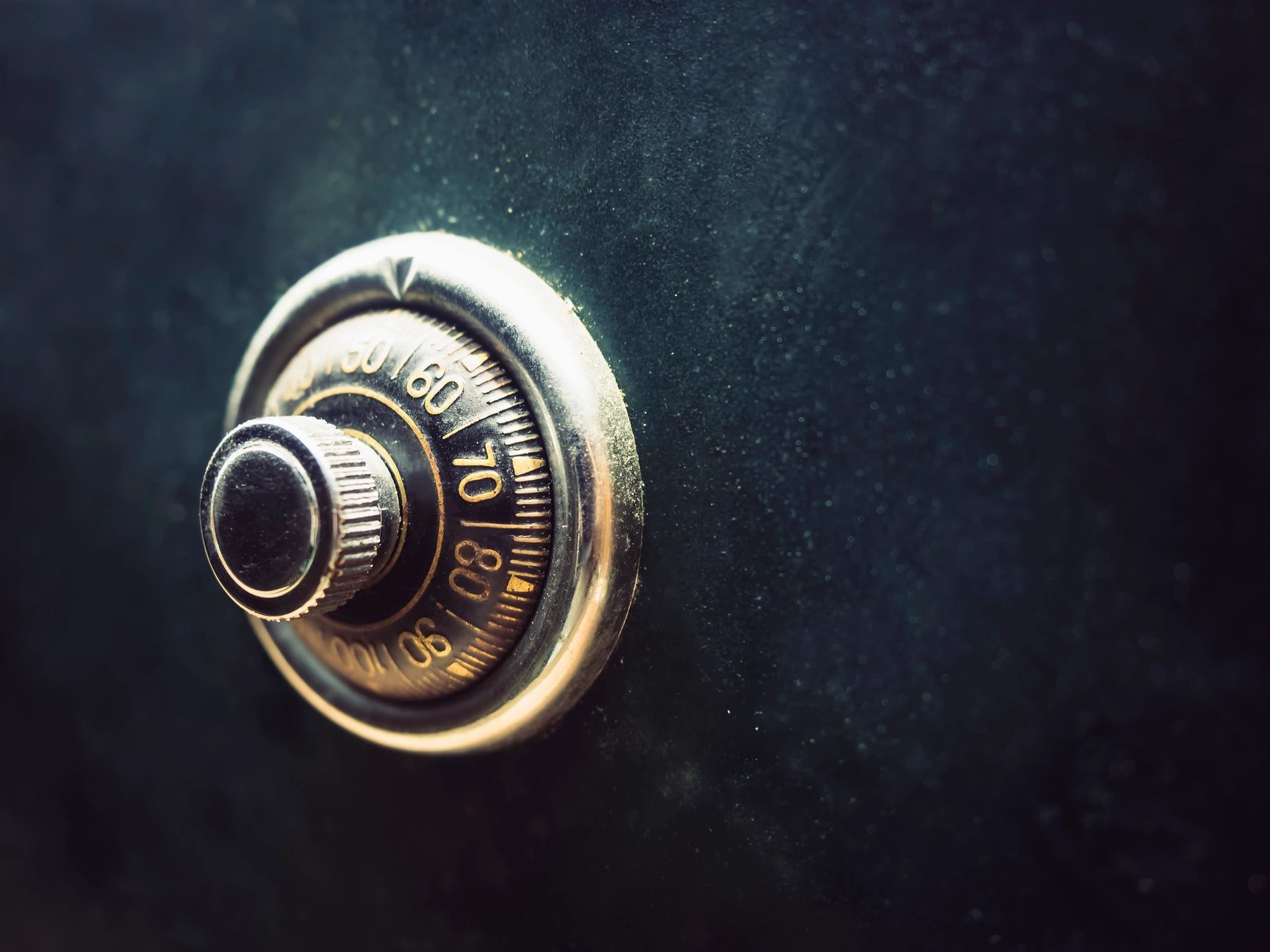 Brass combination lock glowing on a near-black background